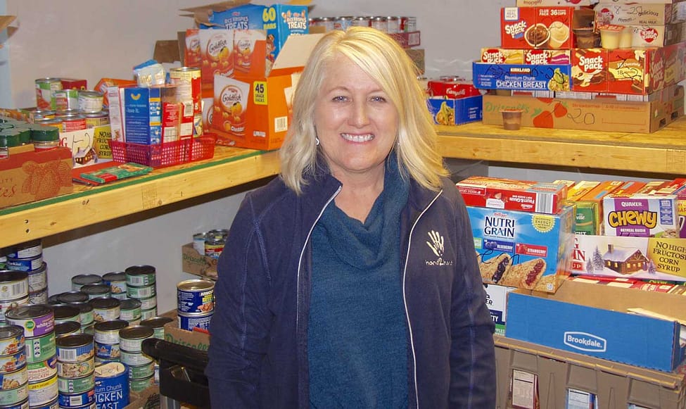 Cheri Hondred standing in front of nutritious food for hungry kids in West Michigan